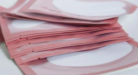 A neat stack of pink hydrogel eye patch sachets for professional lash isolati Stock Photos