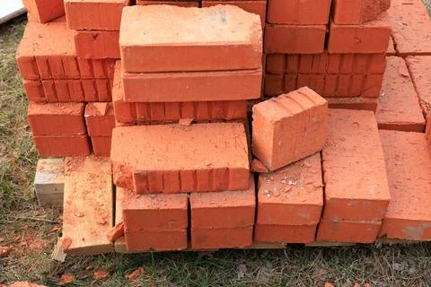 Neat stack of red clay bricks on a wooden pallet at an outdoor building site. Stock Photos