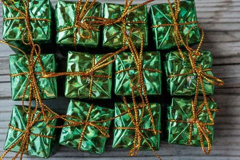 Neatly arranged small gift boxes, wrapped in shiny green foil. Stock Photos
