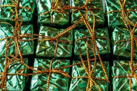 Neatly arranged small gift boxes, wrapped in shiny green foil. Stock Photos