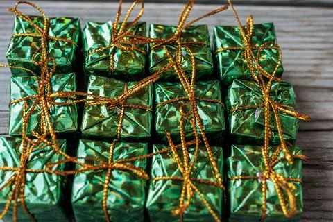 Neatly arranged small gift boxes, wrapped in shiny green foil. Stock Photos