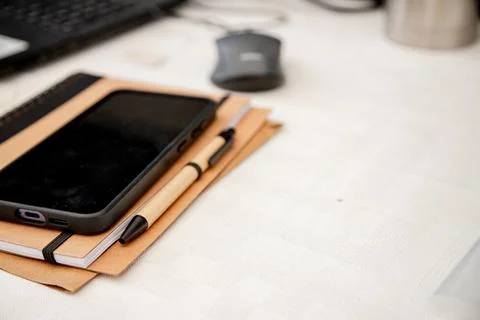A neatly arranged workspace with a smartphone, notebook, and pen on a desk Stock Photos
