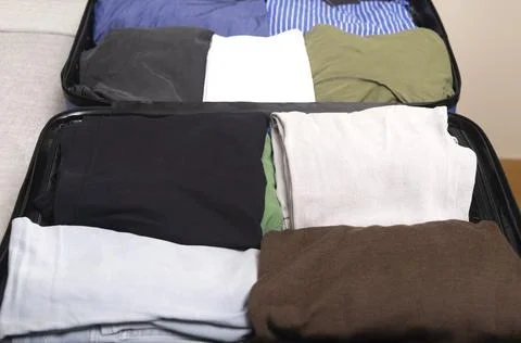 Neatly folded clothes inside organized blue suitcase,Open suitcase with stack Stock Photos