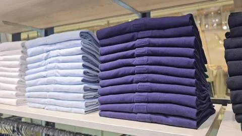 Neatly folded stacks of black, navy and trousers arranged on wooden shelves Stock Footage 313149072