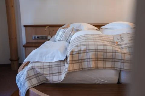 Neatly Made Bed with Plaid Bedding in Alpine Hotel Room in Austria Foto stock