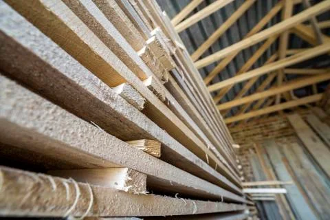 Neatly piled long stack of wooden boards inside attic room under construction Foto stock