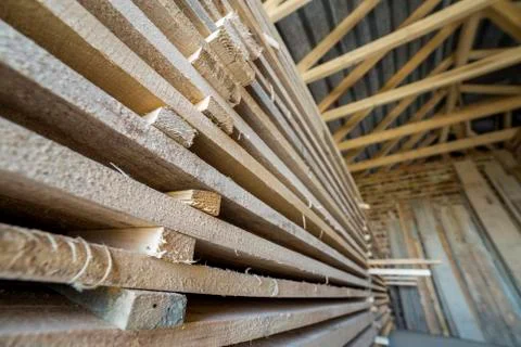 Neatly piled long stack of wooden boards inside attic room under construction Stock Photos