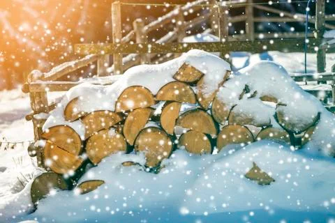 Neatly piled stack of chopped dry trunks wood covered with snow outdoors on b Stock Photos