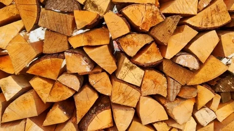Neatly stacked split firewood in bright sunlight, showing golden log faces Stock Footage 336224752