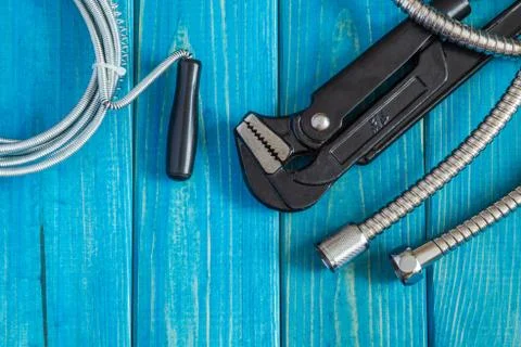 Necessary set of tools and hose for master plumber on blue wooden boards Stock Photos