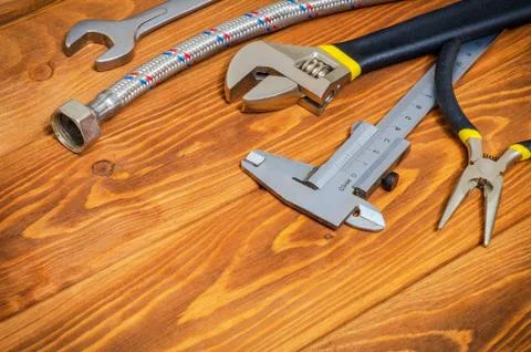 Necessary set of tools and hose for plumbers on vintage wooden boards with sp Stock Photos