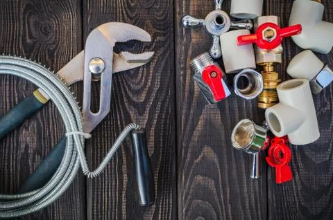 Necessary set of tools and spare parts for plumbers on dark vintage wooden ba Stock Photos