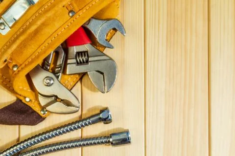 Necessary set of tools in the bag for plumbers on a wooden background. Stock Photos