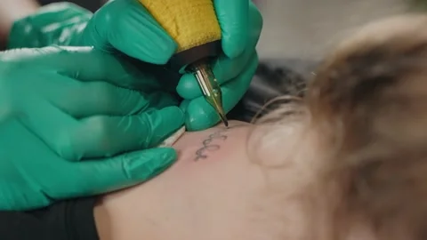 In neck of client master makes tattoo with inscription using tattoo machine. Stock Footage 219549157