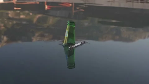The neck of the green bottle floats on the surface of the water. Environmental Stock Footage 220461602