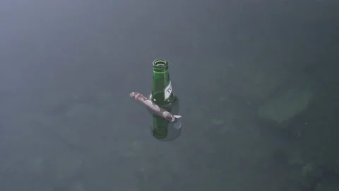 The neck of the green bottle floats on the surface of the water. Environmental Stock Footage 222209512