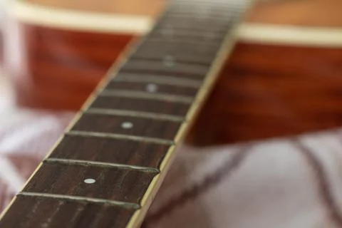 Neck guitar without strings with frets of light wood on a brown plaid Foto stock