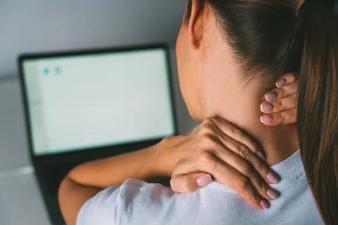 Neck pain after working on a computer. Woman massaging neck to relieve pain Stock Photos