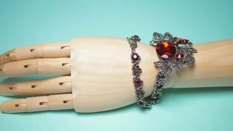 Necklace with ruby ​​hanging on a wooden mock hands. blue background Video stock 124570802
