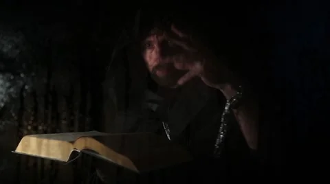 Necromancer casts spells from thick ancient book by candlelight, behind Stock Footage 68630998