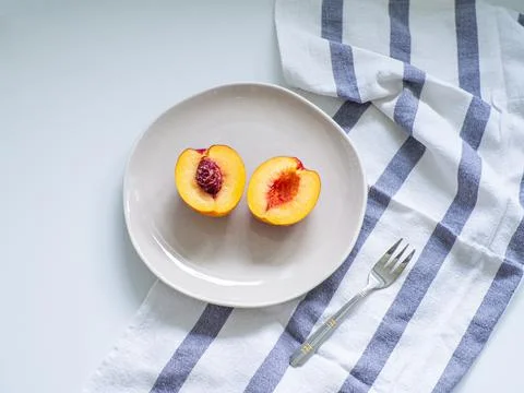 Nectarine on the beige plate with fork on white table Stock Photos