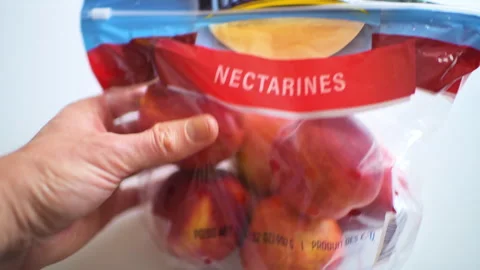 Nectarines nectarine fruit in plastic bag macro closeup hand holding package Vídeo Stock 330176446