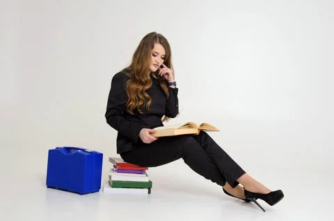Need knowledge woman sitting on stack of books smart watch suitcase tools Stock Photos