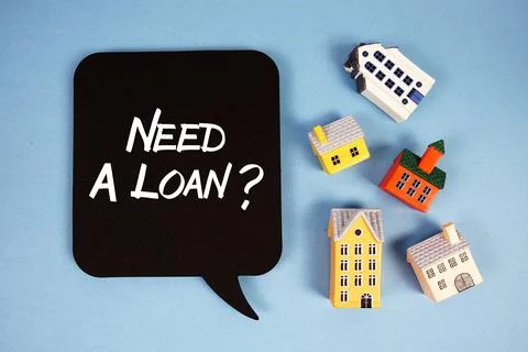 Need A Loan? text with house models on blue background Stock Photos