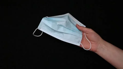 Need to put on a mask. Protective face mask in hand on black background Video stock 167473657
