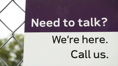 Need to talk were here call us sign in white and black print on purple and white Stock Footage 246611814