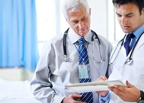 Needing a second opinion. two doctors discussing a case file. Stock Photos