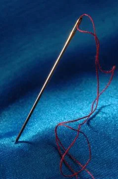 Needle and thread on blue material 스톡 사진