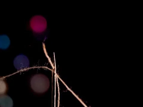Needle and thread in the dark, illuminated by colorful bokeh creating an et.. Stock Photos