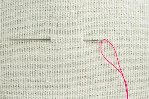 A needle and thread drawn through the fabric Stock Photos