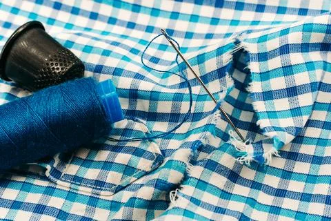 A needle and thread lies on torn or holey clothes. Shirt with a hole. Work .. Foto stock