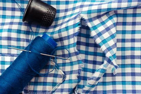 A needle and thread lies on torn or holey clothes. Shirt with a hole. Work .. Stock Photos