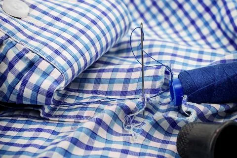 A needle and thread lies on torn or holey clothes. Shirt with a hole. Work .. 写真素材