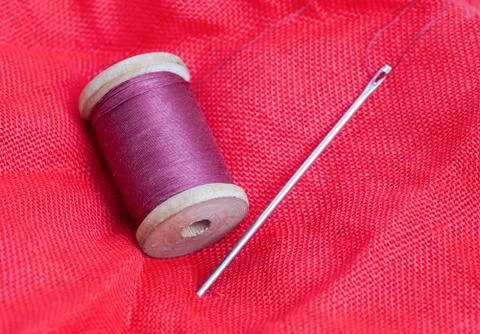 Needle and thread on a red background Stock Photos