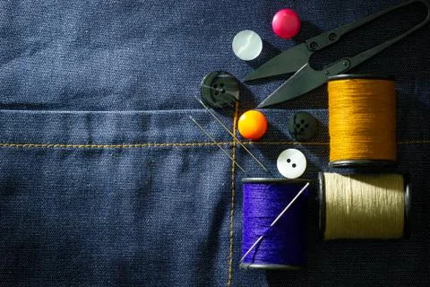 Needle and threads against plastic button and thread cutting scissors. Stock Photos