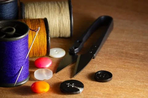 Needle and threads against plastic button and thread cutting scissors. Stock Photos