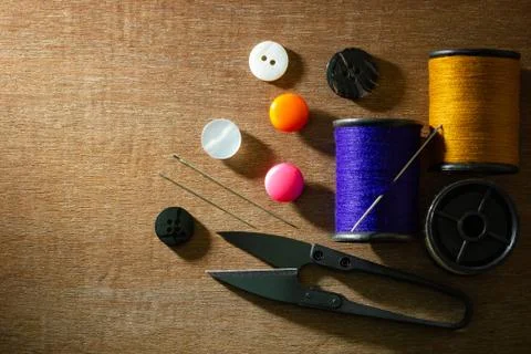 Needle and threads against plastic button and thread cutting scissors. Stock Photos
