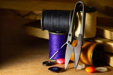 Needle and threads against plastic button and thread cutting scissors. Stock Photos