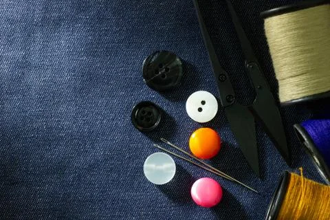 Needle and threads against plastic button and thread cutting scissors. Stock Photos