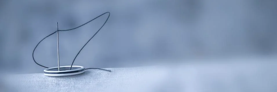 A needle with a black thread pulled in sews Stock Photos