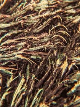 Needle-like crystals under polarized microscope showing vivid birefringence 스톡 사진