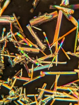 Needle-like crystals under polarized microscope showing vivid birefringence 스톡 사진