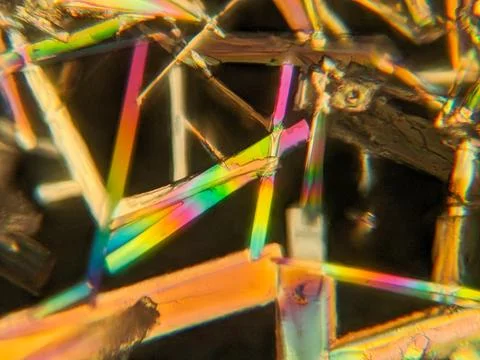Needle-like crystals under polarized microscope showing vivid birefringence Foto stock