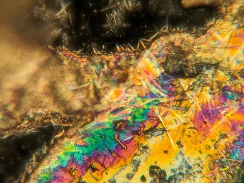 Needle-like crystals under polarized microscope showing vivid birefringence 스톡 사진