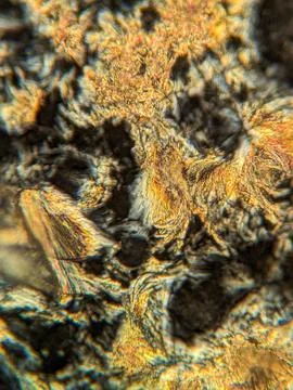 Needle-like crystals under polarized microscope showing vivid birefringence 스톡 사진