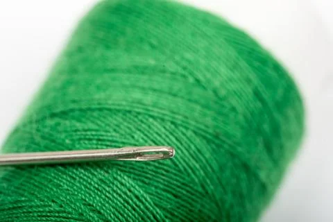 Needle head on the green thread over white background Stock Photos